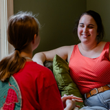 A young foster mom talks to a teen girl at home